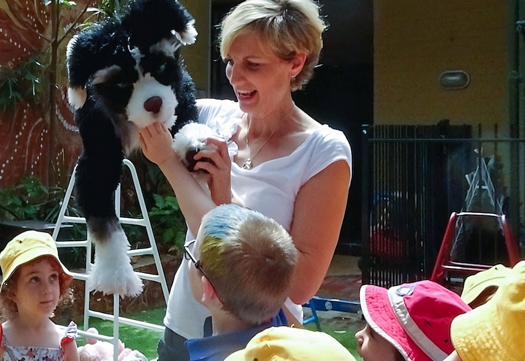 Pup and Emma de Vries guide the kids on a vibrant outdoor exploration. One curious child reaches out, engaging directly with Pup.